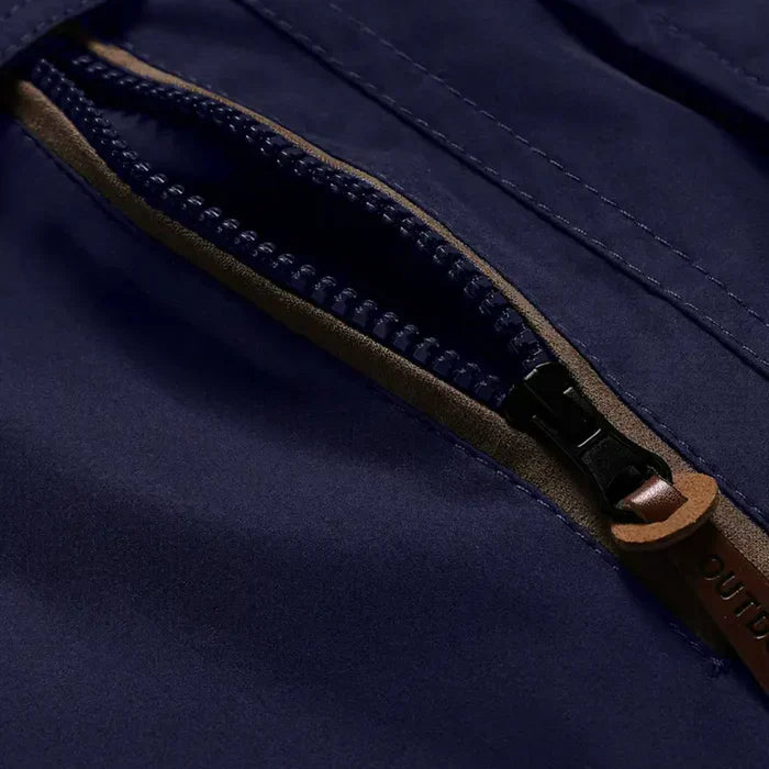 Nahaufnahme eines blauen Outdoor-Jackenreißverschlusses mit braunem Lederanhänger