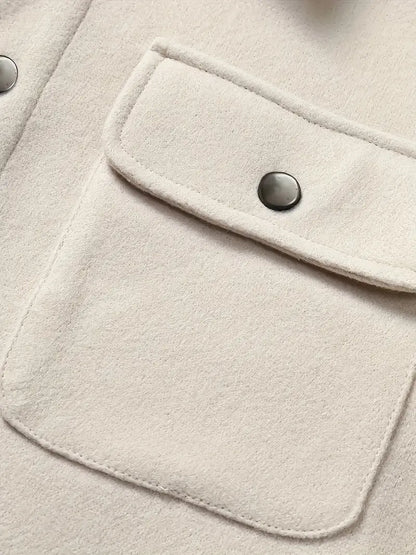 Nahaufnahme einer beigefarbenen Jackentasche mit Druckknopf auf Wollstoff