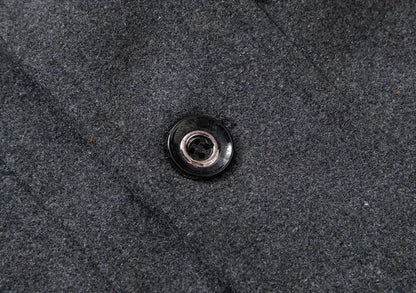 Schwarzer Knopf auf grauem Wollstoff, Detailaufnahme, Modeaccessoire Textil