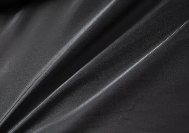 Nahaufnahme von schwarzem, glänzendem Satin-Stoff mit weichen Falten, Stofftextur
