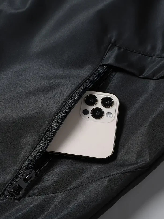 Nahaufnahme einer schwarzen Jackentasche mit Reißverschluss und Smartphone darin