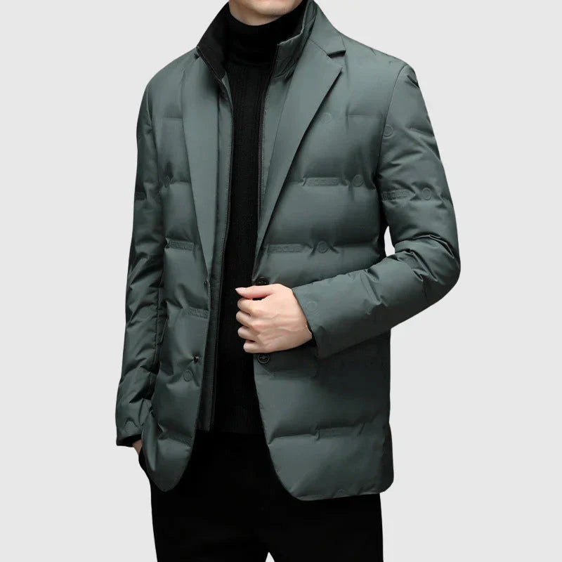 Herren tragen gesteppte grüne Pufferjacke L'Essenziale, modern und elegant, vor grauem Hintergrund.
